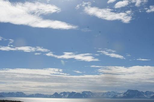Bilde fra Hasvik sett mot sør. Det viser mye blå himmel og litt skyer over fjellene.